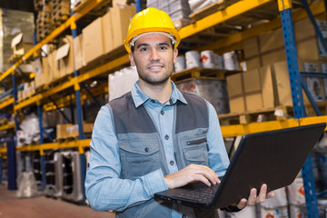 workman using laptop at warehouse