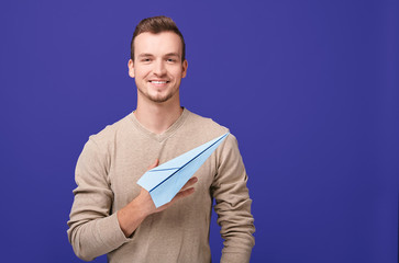 A handsome guy with a smile holds a paper plane.