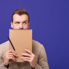 Handsome man holds a brown notebook.