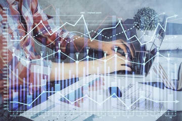 Double exposure of stock graph with businessman typing on computer in office on background. Concept...