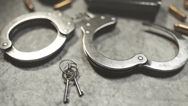 Handcuffs with lock keys and magazine of a pistol. Camera focuses on keys. 4KHD