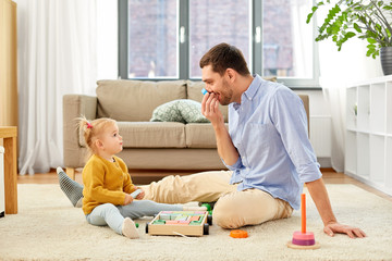 family, fatherhood and people concept - happy father and little baby daughter playing with wooden...