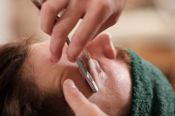 a barber shaves a man with a beard with a dangerous blade. 