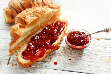 Sweet breakfast. Croissant with raspberries. Raspberry jam in a silver spoon and a bowl. Fragrant...