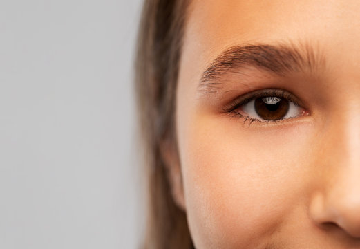 beauty, vision and people concept - close up of teenage girl face with brown eyes over grey background