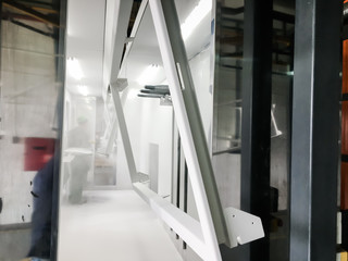 Powder coating line. Metal panels are suspended on an overhead conveyor line. Painting products in...