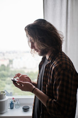 Fototapeta na wymiar Young bearded man using phone at home