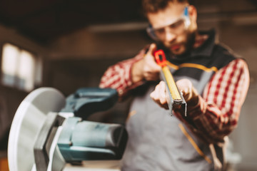 Young man work in home workshop measures a metal pipe