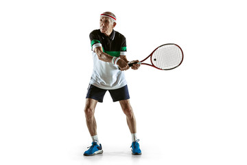 Senior man wearing sportwear playing tennis isolated on white background. Caucasian male model in great shape stays active and sportive. Concept of sport, activity, movement, wellbeing. Copyspace, ad.