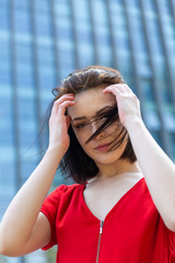 portrait of a brunette girl in a red dress on a background of a blue building