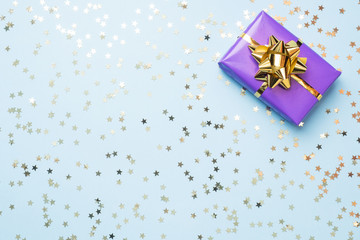 Flat lay background for celebration Christmas and New Year. Gift boxes are purple with gold ribbons bows and confetti stars on a blue background. top view copy space. - Powered by Adobe