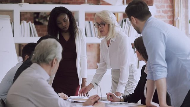 Old woman mentor teaching staff explaining project plan at meeting