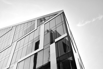 Modern office building wall made of steel and glass with blue sky. Black and white.