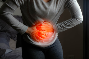 Asian girl stand and hold hand at stomach ache like symptoms specific to indigestion, abdominal...