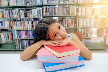 European small schoolgirl, white skin, long light brown hair sleep in the library on many old books. She's smiling when was imagine about fairy tale read just finished, blurred background,window light