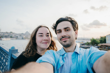 Couple makes selfie on the bridge against the background of the city.