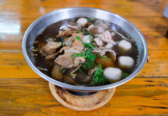 Pork soup consists of fresh and stewed pork, meatball, black soup prepare from Chinese medicine in a metal pot, useful nutrients. Eat with fresh vegetable and rice, not spicy and not have noodle line.