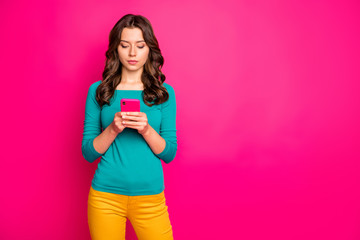 Naklejka premium Photo of pondering pensive thoughtful girl reading feedback left by subscribers analyzing found information with serious facial expression holding telephone isolated vibrant color background