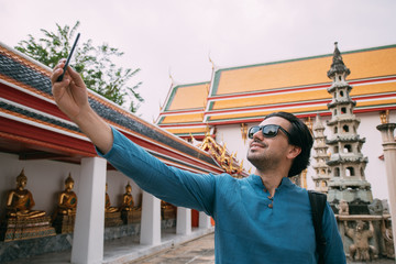 A man in a Buddhist temple takes pictures, takes a selfie on the phone.