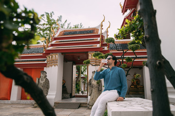 A young man is resting, drinking water in a Buddhist temple.