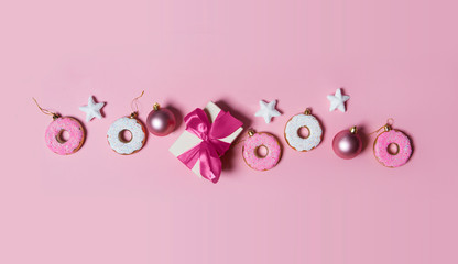 Christmas decoration balls, donuts, gift and stars  on pink background. flat lay, top view. Christmas card conception. 