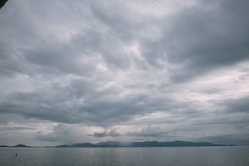 Dark, cloudy sky in the ocean and rain over the island.