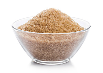 Glass bowl of natural brown refined sugar on white background.