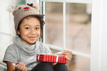 Happy adorable african american child girl opens a christmas present in a red box 