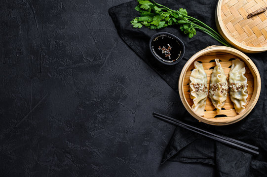 Korean dumplings in a traditional bamboo steamer. Top view. Space for text. rustic old vintage black background