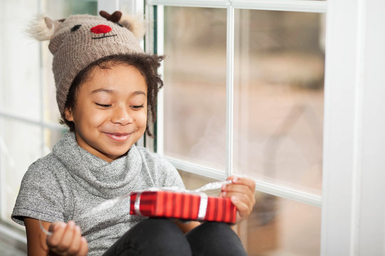 Happy adorable african american child girl opens a christmas present in a red box 