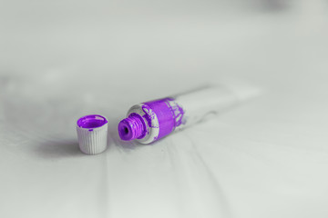 Purple colored tube on floor, isolated on white background