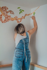 Young female artist dressed in work robe, jeans white and t-shirt