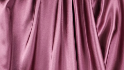 Dark pink satin fabric is draped with vertical soft folds, background