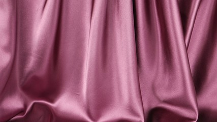 Dark pink satin fabric is draped with vertical soft folds, background