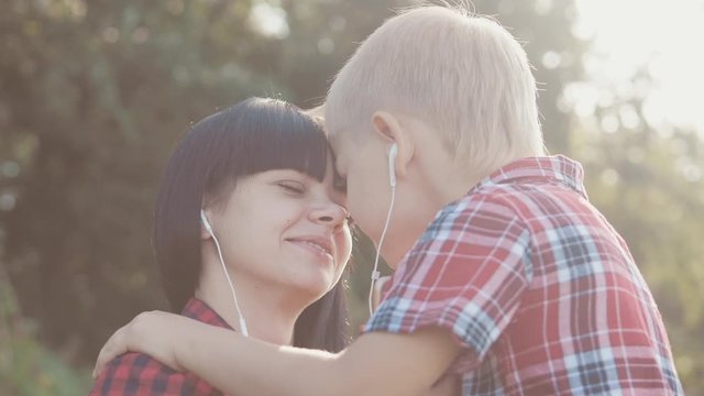 happy family funny nature slow motion video teamwork outdoors. Mom and son lifestyle listen to music on smartphone in the same headphones for two . happy family mother woman and son little boy spend