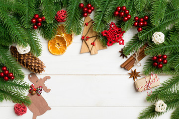 Fototapeta premium Top view of fir tree branches and festive decorative toys on wooden background. New Year time concept with empty space for your design