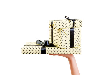 Woman hands give wrapped group of Christmas or other holiday handmade present in yellow paper with black ribbon. Isolated on white background, top view. thanksgiving Gift box concept