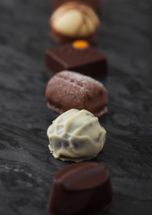 Luxury Chocolate candies selection on black marbel board. White, dark and milk chocolate assortment.