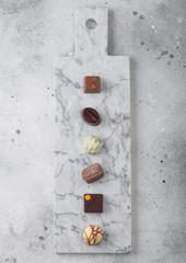 Luxury Chocolate candies selection on light marbel board. White, dark and milk chocolate assortment.
