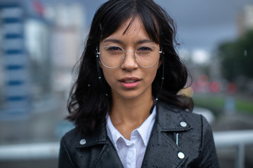 The girl stands in the beginning rain and stares into the camera.