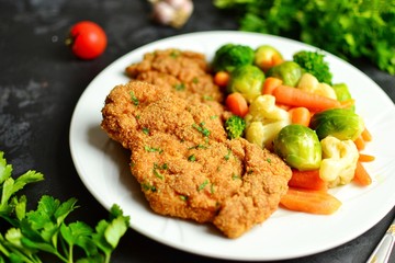 Chicken breast and vegetables. Grilled, baked chicken breast with carrots, brussels sprouts and broccoli. Meat in a white plate on a dark background isolated.