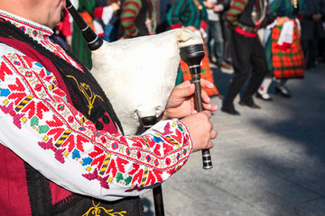 A man in a traditional Bulgarian costume plays an ancient musical folk wind instrument - bagpipes...