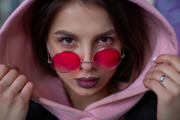 Beauty in crimson glasses looks at you from the hood of a powdery hoodie