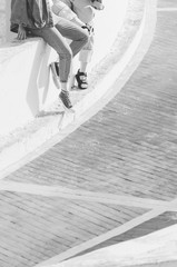 Black and white shot of Feet of friends sitting together. Cropped portrait of two girl. Top view of shoes of hipsters resting.