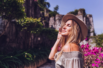 Beautiful excited blonde woman walks and admires tropical landscapes at paradise island hotel in Sanya, China. Luxury vacation resort concept banner. Asia travel lifestyle tourist