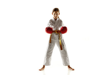 Confident junior in kimono practicing hand-to-hand combat, martial arts. Young female fighter with...