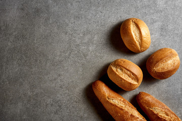Homemade cakes. Freshly baked baguettes and buns on a gray stone surface. Top view.