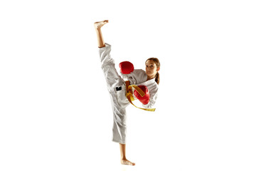 Confident junior in kimono practicing hand-to-hand combat, martial arts. Young female fighter with yellow belt s training on white studio background. Concept of healthy lifestyle, sport, action.