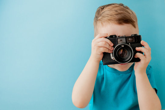 Little boy with an old camera on a blue background