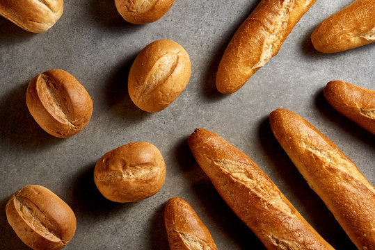 Fresh bakery. French baguettes and buns on a gray stone surface. Top view.